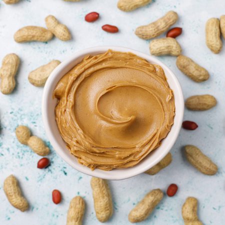 Homemade peanut butter with peanuts on grey concrete background,top view